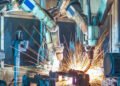 Humanoid robot working alongside humans in modern factory