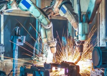 Humanoid robot working alongside humans in modern factory