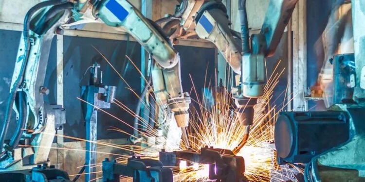 Humanoid robot working alongside humans in modern factory