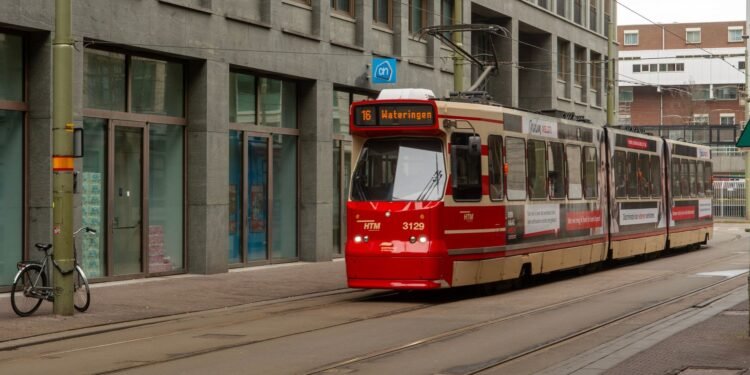 A red HTM tram on a street in The Hague