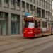 A red HTM tram on a street in The Hague