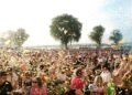 Crowd at an outdoor music festival with confetti on a sunny day