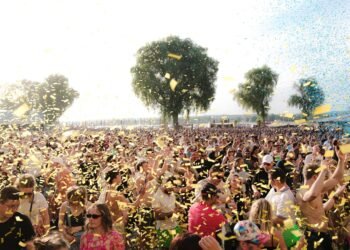 Crowd at an outdoor music festival with confetti on a sunny day