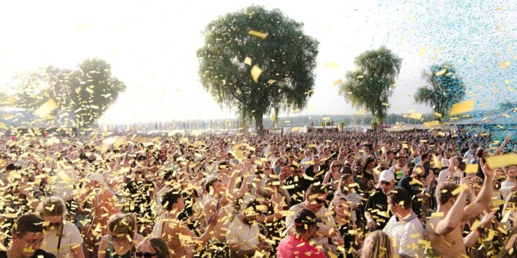Crowd at an outdoor music festival with confetti on a sunny day
