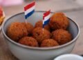 Dutch bitterballen in a bowl with small Dutch flags on a cafe terrace