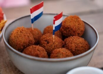 Dutch bitterballen in a bowl with small Dutch flags on a cafe terrace