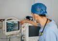 Clinician in scrubs reviewing data on a monitor