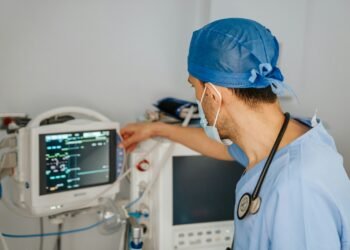 Clinician in scrubs reviewing data on a monitor
