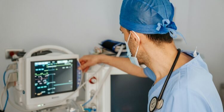 Clinician in scrubs reviewing data on a monitor
