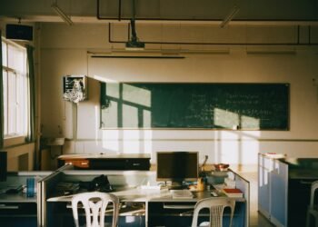 Sunlight streaming into an empty classroom with rows of desks