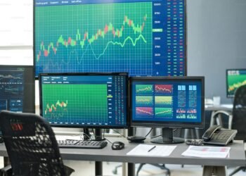 Empty trading desk with multiple monitors showing market data