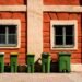 Green wheelie bins lined up outside a brick house