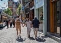 Shoppers walking along a pedestrian shopping street with a tram