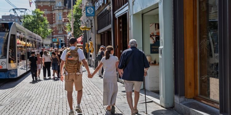 Shoppers walking along a pedestrian shopping street with a tram