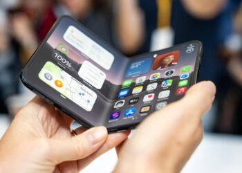 iPhone Duo foldable held open in two hands showing the iOS home screen